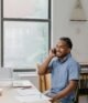 Adult man engaged in office work, speaking on phone, showcasing a professional environment.