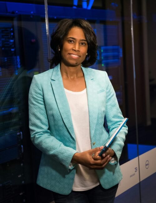 Confident woman in a server room, holding a tablet. Ideal for tech and business themes.