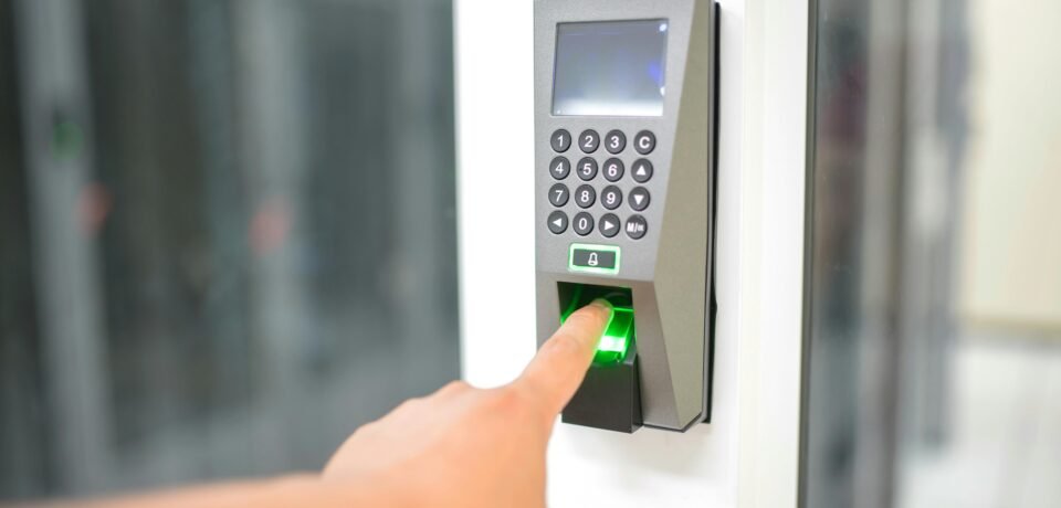 A person uses a fingerprint scanner for secure entry in a business setting.