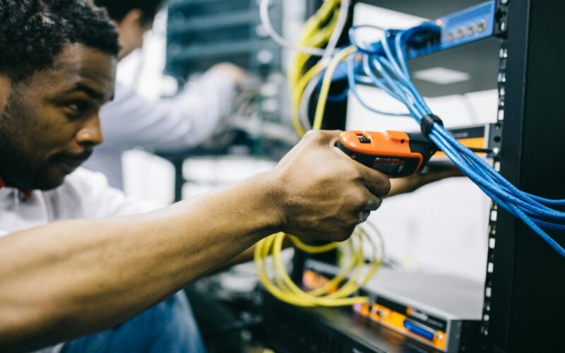 Side view crop concentrated African American engineer repairing equipment by using electric screwdriver