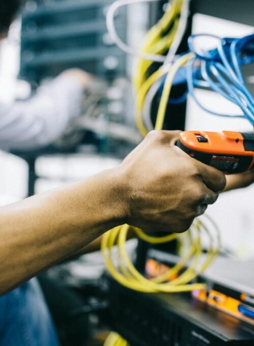 Side view crop concentrated African American engineer repairing equipment by using electric screwdriver