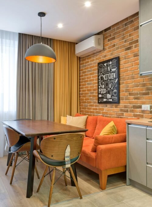 Modern kitchen with brick wall and minimalist furniture in a cozy apartment.