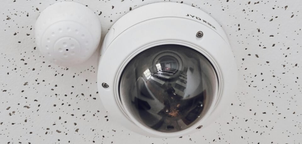 Close-up of a round dome surveillance camera installed on a speckled ceiling for security monitoring.