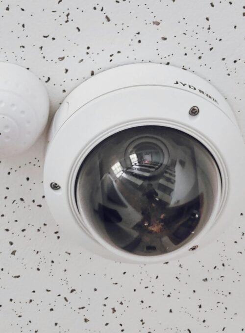 Close-up of a round dome surveillance camera installed on a speckled ceiling for security monitoring.