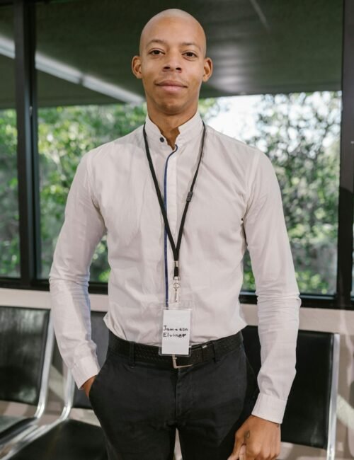 A confident businessman in a white shirt stands indoors at a conference.